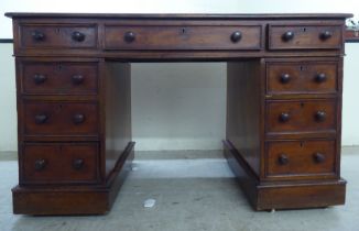 A late Victorian mahogany nine drawer, twin pedestal desk, the top set with a brown hide scriber, on