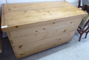 A mid 20thC waxed pine chest with straight sides and a hinged lid, on a plinth and casters  24"h