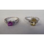 Two white metal rings, one set with a yellow citrine, the other with a pink heart shaped stone