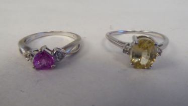 Two white metal rings, one set with a yellow citrine, the other with a pink heart shaped stone