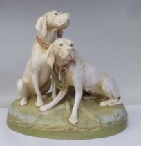 A Royal Dux porcelain model, a pair of seated hounds, on an oval, naturalistically moulded plinth,