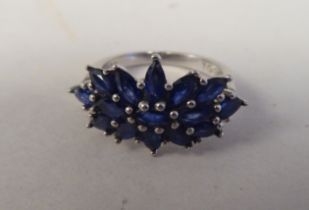 A white metal cluster ring, set with oval cut sapphires  stamped 925