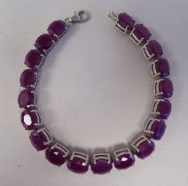 A white metal bracelet, set with rivetted oval cut rubies  stamped 925
