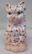 A 20thC porcelain model, a seated cat, decorated in iron red with blue eyes  6.75"h