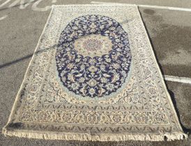 An Iranian Nain woollen rug with stylised motifs, on a beige ground  120" x 78"