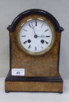 An early 20thC part lacquered walnut cased mantel clock with a round arch top and flank windows,