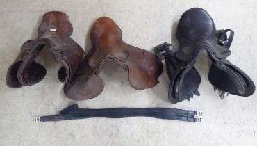 Two brown hide horse saddles; and another in black hide