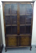 A mid 20thC walnut bookcase with two glazed doors and two panelled doors, raised on cabriole legs