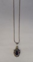 A white metal pendant, set with a raised teardrop cut garnet, on a white metal chain  stamped 800