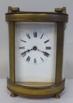 An early 20thC French oval brass cased carriage timepiece with bevelled glass panels and a folding