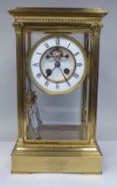A late Victorian lacquered brass, four glass mantel clock with bevelled panels; the visible bell