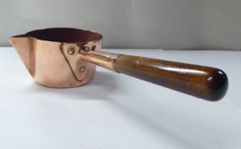 A 19thC copper chocolate saucepan with a spout, rivetted and turned wooden handgrip  4.5"dia