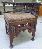 A late 19thC Moorish mother-of-pearl inlaid fruitwood corner chair with an upholstered seat,