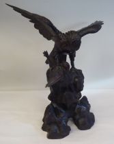 A cast and patinated bronze model eagle, on a rock with captured prey  16"h