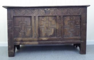 A 17thC boarded oak coffer with a tri-panelled front, incorporating lunette and foliate carved