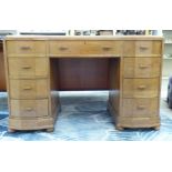 An Art Deco period light oak nine drawer inverted breakfront twin pedestal desk with a maroon hide