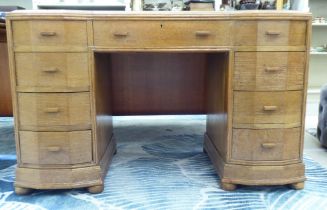An Art Deco period light oak nine drawer inverted breakfront twin pedestal desk with a maroon hide