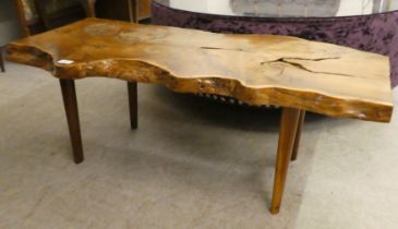 A rustically constructed waxed elm coffee table of natural form, raised on tapered legs  16"h  42"w