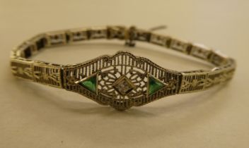A white metal (stamped 14k) fine wire hinged bracelet, set with a central diamond and green stones