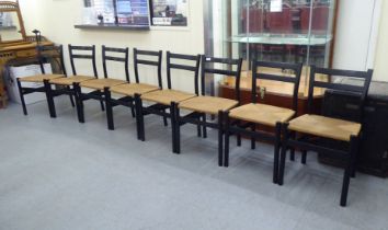 A set of eight modern black painted, twin bar back chairs with rush seats