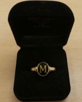 A yellow metal ring, set with a black stone with the letter M