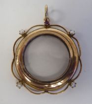 A yellow metal open locket, the glazed circular centre adorned with pearls and a garnet, on a