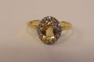 An 18ct bi-coloured gold ring, set with a central yellow stone, surrounded by small diamonds