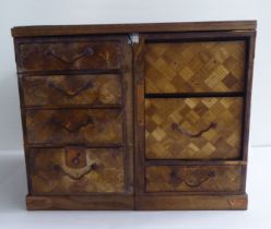 An early 20thC oak parquetry desk tidy, fashioned as a twin pedestal desk with two banks of seven