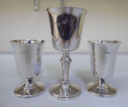 A pair of modern silver goblets, the inverted bell shaped bowls on domed pedestals; and another of