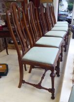 A set of six early 20thC oak framed dining chairs, the fabric upholstered drop-in seats raised on