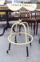 A cream painted cast metal tractor seat design bar stool