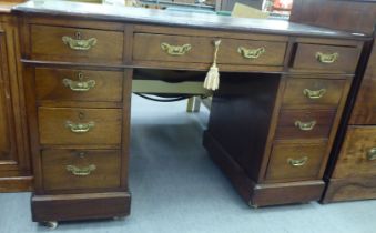 An early 20thC mahogany nine drawer, twin pedestal desk, the top set with a green hide scriber, on a