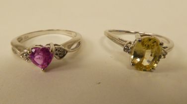 Two white metal rings, one set with a yellow citrine, the other with a heart shaped pink stone