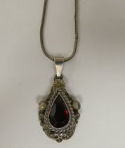 A white metal pendant, set with a teardrop cut garnet, on a white metal chain  stamped 800