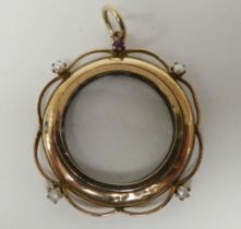 A yellow metal open locket, the glazed circular centre adorned with pearls and a garnet, on a