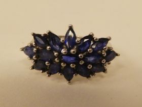 A white metal cluster ring, set with oval cut sapphires  stamped 925