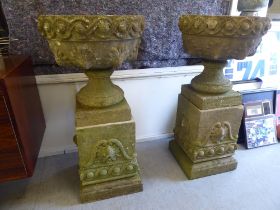 A pair of composition stone garden urns, each on a plinth  40"h