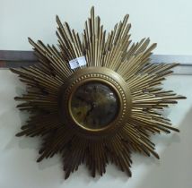 A mid 20thC composition sunburst clock; the quartz movement faced by a Roman dial  19"dia