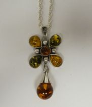 A white metal pendant, fashioned as a cross, set with amber coloured beads, on a white metal