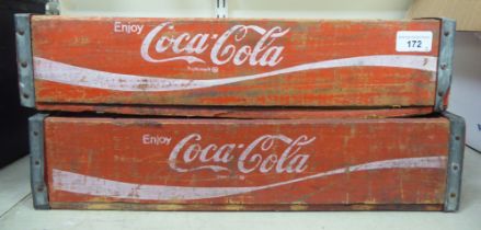 A pair of red stained pine Coco-Cola bottle trays with iron re-enforcement and twenty-four apertures