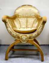 An early 20thC Savonarola inspired chair, upholstered in old gold coloured floral patterned fabric