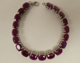 A white metal bracelet, set with rivetted oval cut rubies  stamped 925