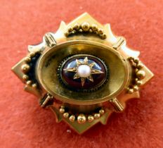 A late Victorian yellow metal garnet and pearl set brooch