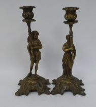 A pair of cast brass candlesticks, respectively featuring a man and a woman wearing 18thC costume,