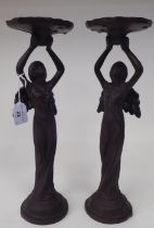 A pair of Victorian style black painted and decoratively cast figural candlesticks, each depicting a