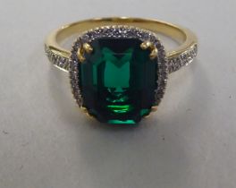 A yellow metal claw set ring with synthetic emeralds and diamond shoulders  stamped 750