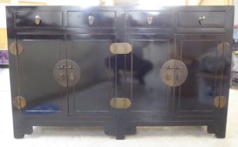 A modern Japanese inspired black painted sideboard with four inline drawers, over four doors, raised