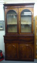 A mid Victorian mahogany cabinet bookcase with a straight cornice, over a pair of glazed doors,