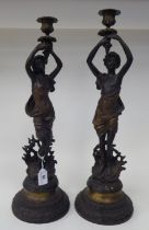 A pair of French style bronze effect figural candlesticks, each featuring a maiden, holding aloft