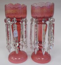 A pair of late 19thC gilded cranberry coloured glass lustre vases, the bowls with castellated